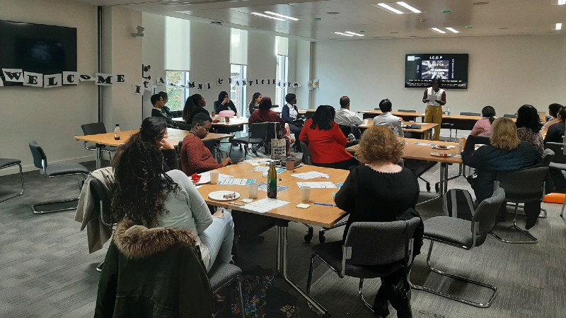 Room shot of ICDP alumni and participants sitting around tables in groups 