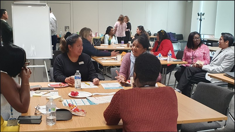 ICDP alumni and participants sitting around tables in groups talking