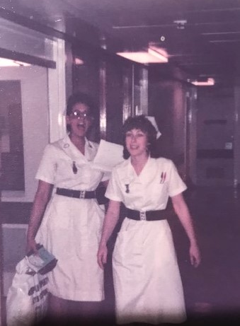 Sharon Hodgson (left) and another nurse, both wearing white uniforms, standing in a hospital corridor.