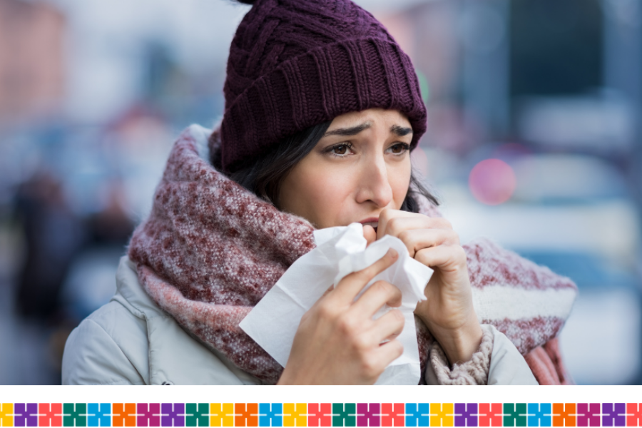 woman wrapped up warm coughing in to a tissue