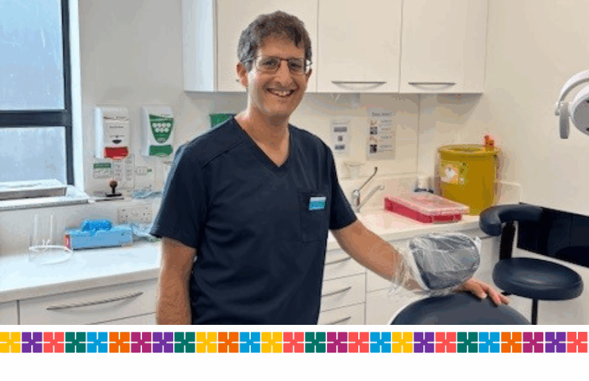 Lead dentist, Dr Scott Aaron is standing behind a dentist's chair