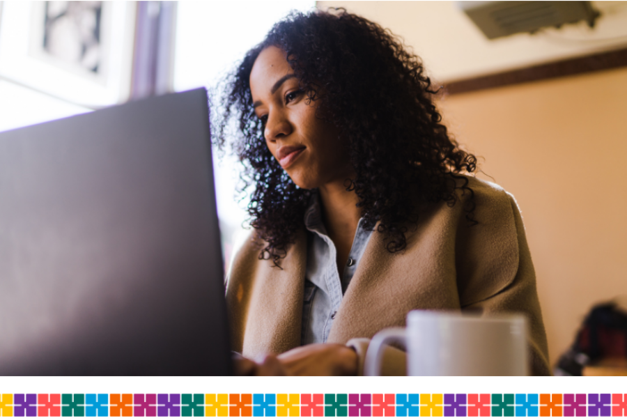 A woman sitting at a desk using a laptop, with a mug in the foreground.